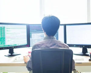 Programista pracuje przy dwóch monitorach.