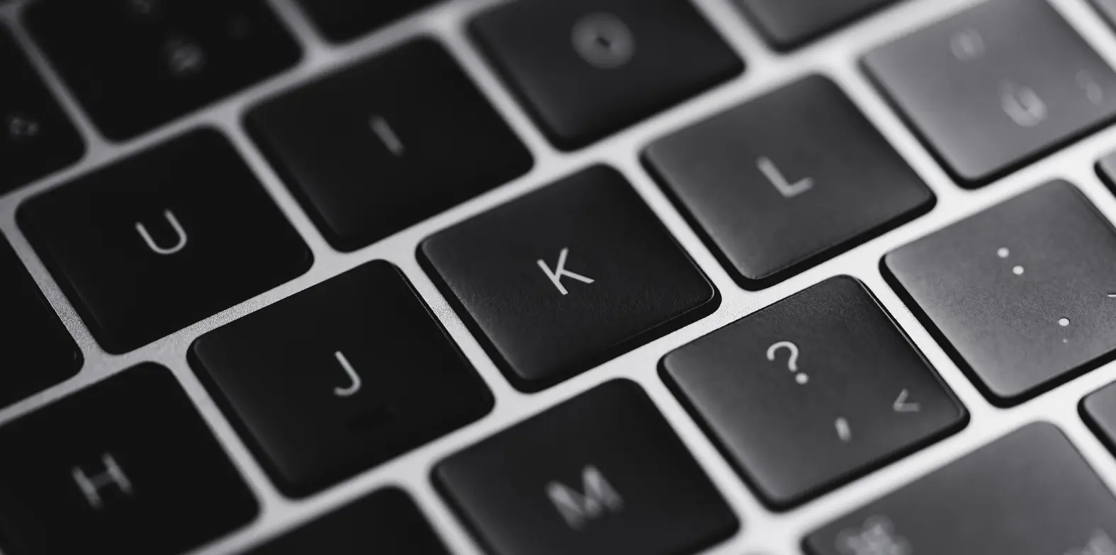 Czarny laptop, klawiatura, przyciski "J", "K", "L".