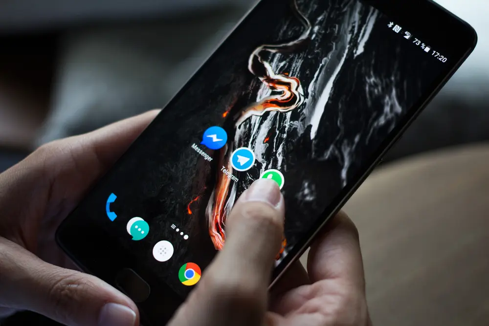 Ręka używająca smartfona z aplikacjami.