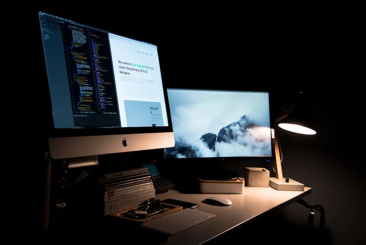 Biurko z komputerem Apple i kodem programistycznym.
